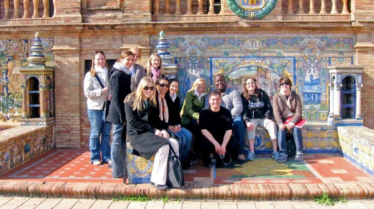 一群学生在一座用彩色瓷砖和砖块砌成的建筑前摆姿势
