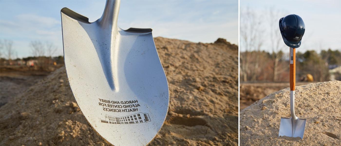 A collage of a shovel standing upright in a mound of dirt with a U N E construction hat on the top of the handle next to a close-up of the shovel's blade with an inscription, "Harold and Bibby Alfond Center for 健康 科学s"