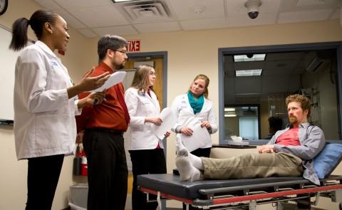 UNE students work with a standardized patient in the simulation lab